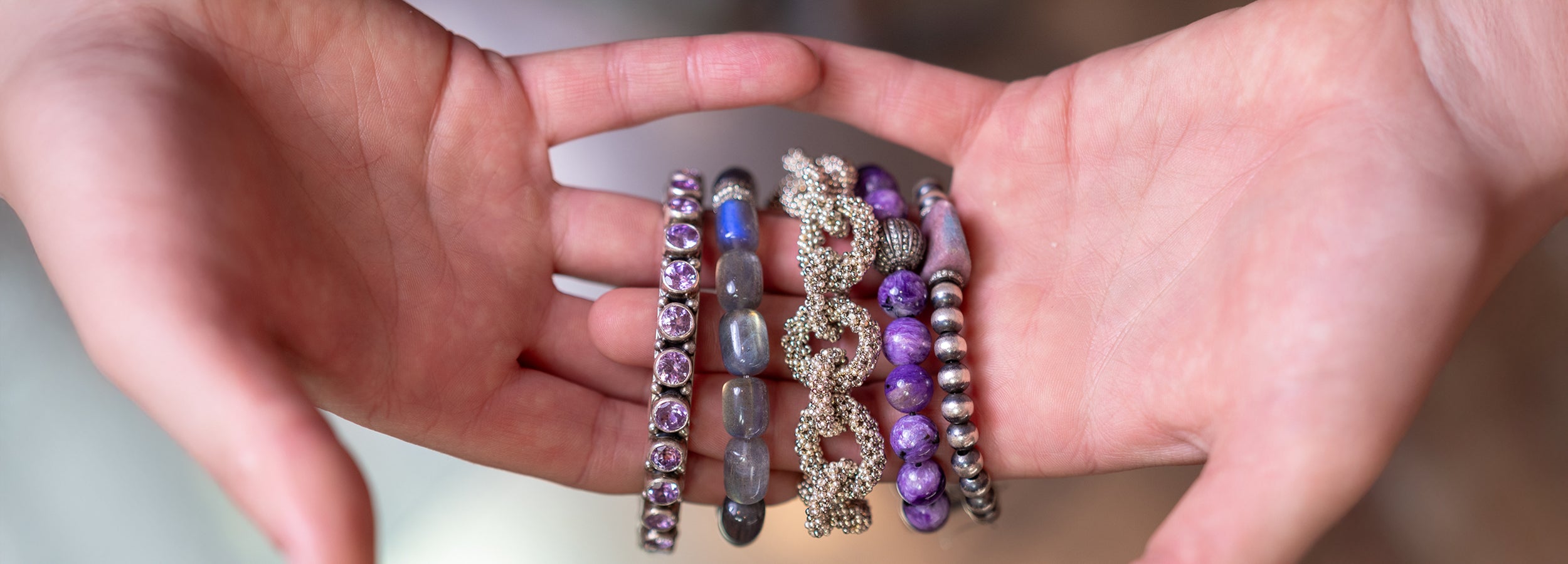 Hands holding handcrafted gemstone jewelry from Sukhmani's curated collection of artisan adornments, Native American jewelry, and treasures from India and around the world.